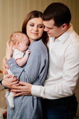 Mom and Dad hold in their arms the infant. 