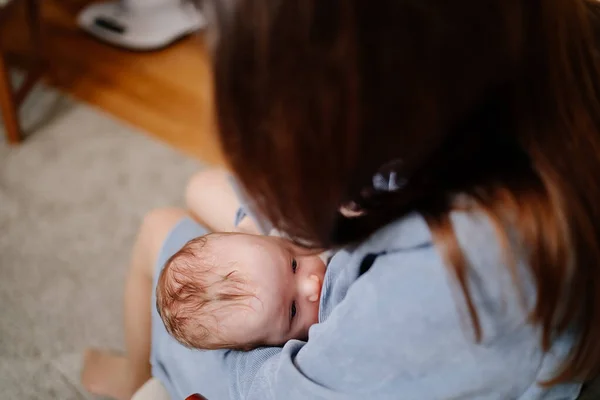 Annem yeni doğmuş bir bebeği evde, kanepede emziriyor. Emzirmenin faydaları — Stok fotoğraf