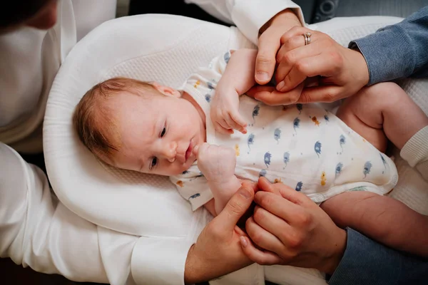 Vista superior. Pais felizes pais dão as mãos filho jovem em uma espreguiçadeira para recém-nascidos. — Fotografia de Stock