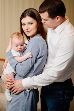 Mom and Dad hold in their arms the infant. 