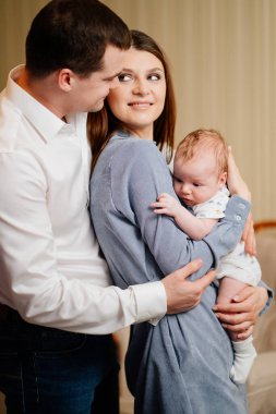 Mom and Dad hold in their arms the infant. 