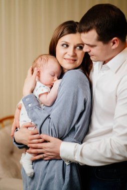 Mom and Dad hold in their arms the infant. 