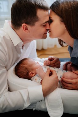 Happy parents with young son in a lounger for newborns. loving family