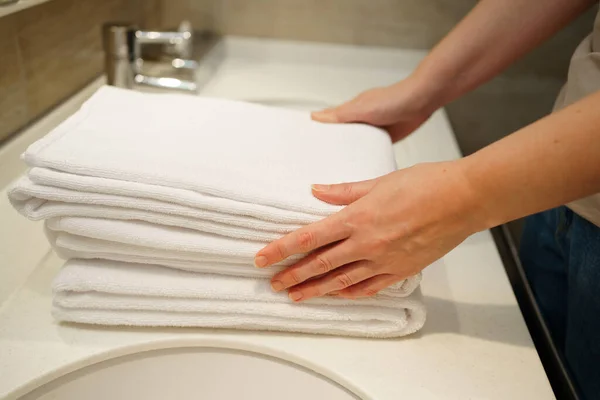Mãos de mulheres com toalhas brancas limpas na mão. Substituição de acessórios de banho. — Fotografia de Stock