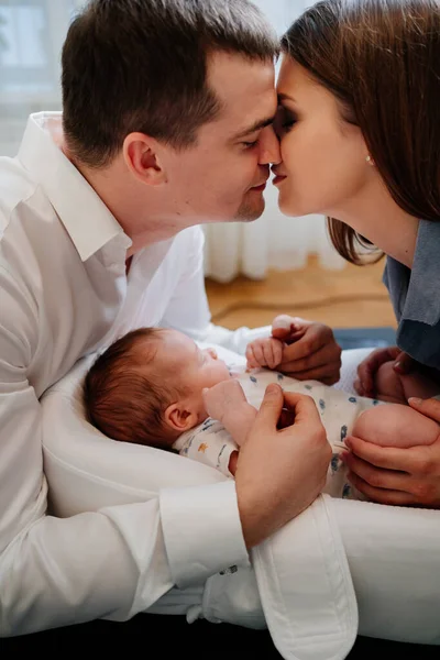 Padres felices con hijo pequeño en una tumbona para recién nacidos. familia amorosa —  Fotos de Stock