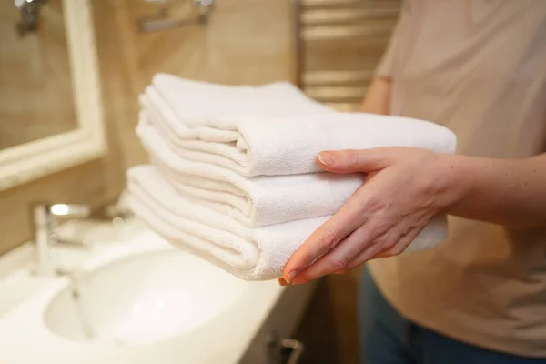 Womens hands with clean white towels in hand. Replacing bath accessories. — Stok fotoğraf