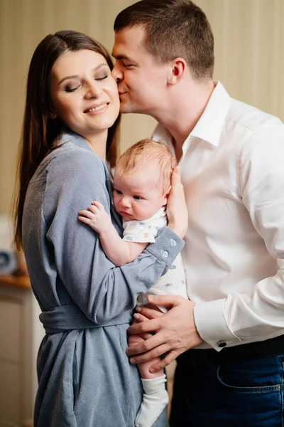 Mom and Dad hold in their arms the infant. 