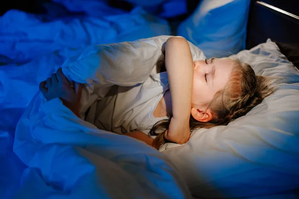어린 소녀는 병들어 침대와 기침을 하며 누워 있습니다. 병중에 잠을 이루지 못한다. — 스톡 사진