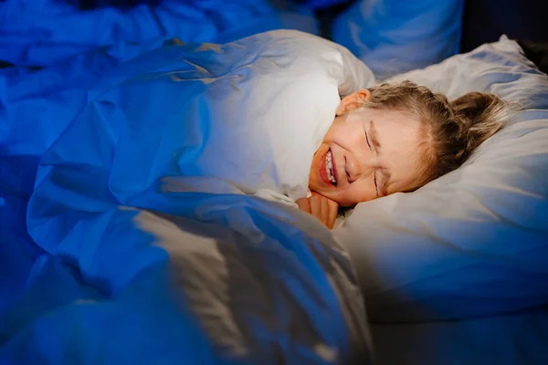 Una bambina dorme a letto, vede un incubo nel sonno — Foto Stock