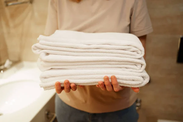 Womens hands with clean white towels in hand. Replacing bath accessories. — Stok fotoğraf