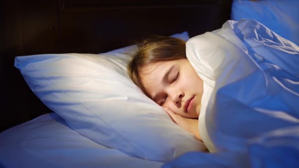 Hezká dospívající dívka spí v posteli, vidí příjemný spánek a usmívá se v noci. — Stock video