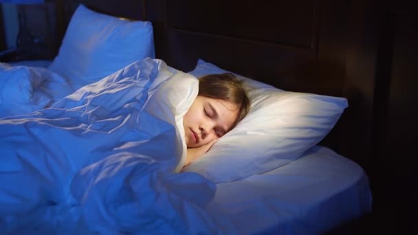 Das Teenager-Mädchen schläft im Bett, sieht einen angenehmen Schlaf und lächelt nachts. — Stockvideo