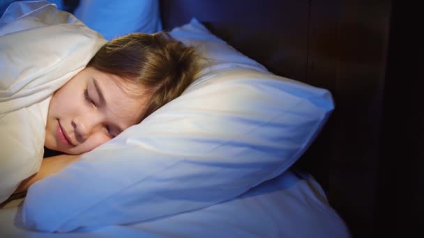 La chica adolescente bonita siesta en el dormitorio, ve un sueño agradable y sonríe — Vídeos de Stock