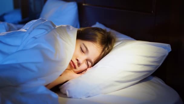 Ένα γλυκό κορίτσι κοιμάται στο κρεβάτι στο δωμάτιό της, βλέπει έναν εφιάλτη και ανεμίζει στον ύπνο της. — Αρχείο Βίντεο