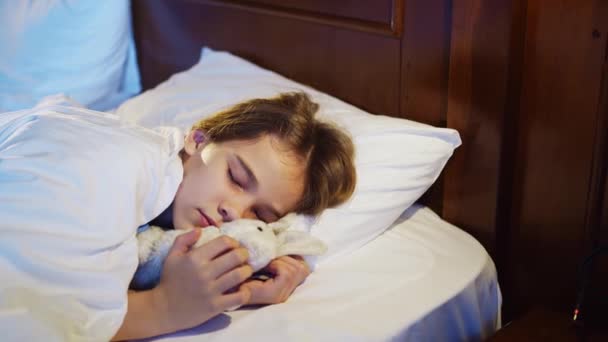 Den vackra tonårstjej sover med en plysch leksak, ser en behaglig sömn och ler. — Stockvideo