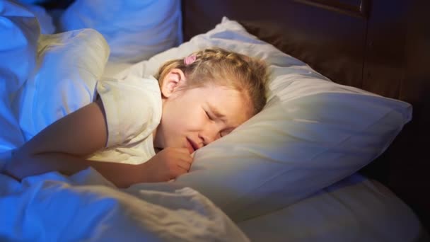 Ein süßes kleines Mädchen schläft im Bett, sieht einen Albtraum und zuckt im Schlaf — Stockvideo