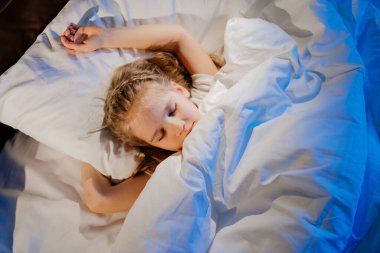 top view. pretty girl naps in bed, sees pleasant sleep and smiles.