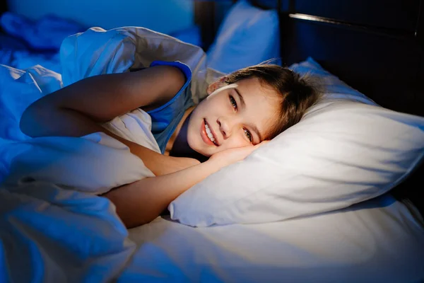 Una ragazza è sdraiata a letto e sorride. sonno dei bambini calmo e sano — Foto Stock