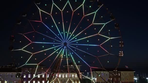 Ferris wiel met gloeiende veelkleurige lichten tegen de nachtelijke hemel. — Stockvideo