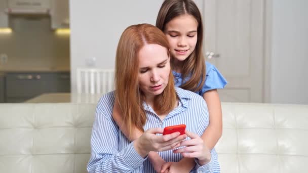 Moeder en dochter op een smartphone, bekijk foto 's, video' s via internet — Stockvideo