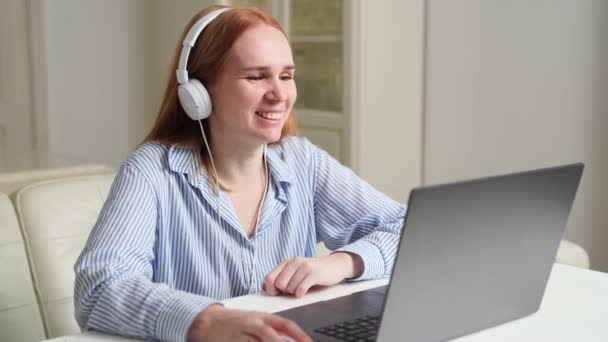 Vrouw met hoofdtelefoon werkt thuis op een laptop leidt een les of webinar. — Stockvideo