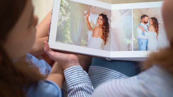 Ansicht von oben. Mutter und Tochter blättern im Hochzeits-Fotobuch. — Stockvideo