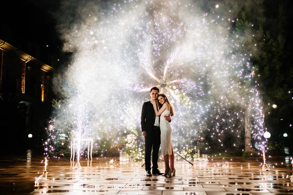 Nevěsta a ženich stojí na chodbě fontán ohňostroje — Stock fotografie