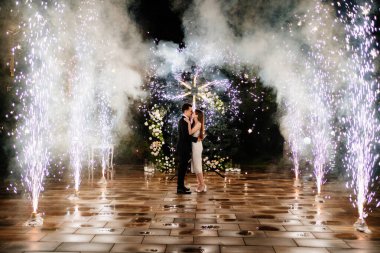Gelin ve damat havai fişek çeşmesinin koridorunda duruyorlar.