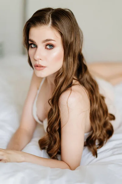 Nahaufnahme. Porträt einer schönen Frau mit langen Haaren in Unterwäsche, die auf dem Bett liegt. — Stockfoto