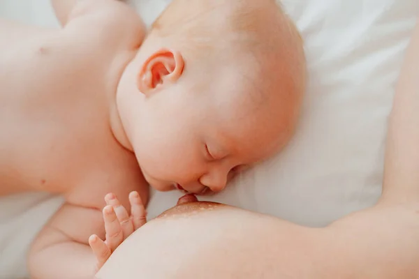 De cerca. mujer desnuda está acostada con el bebé en la cama blanca después de alimentar a la leche materna. —  Fotos de Stock