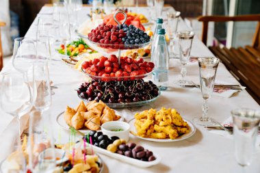 table served with light summer snacks-fruits, vegetables, berries. 