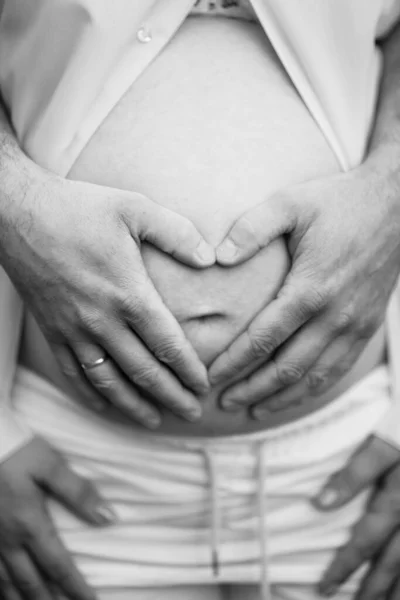 Svartvitt. män händer på magen på en gravid kvinna. — Stockfoto