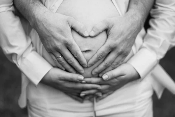 Preto-branco. homens mãos na barriga de uma mulher grávida. — Fotografia de Stock