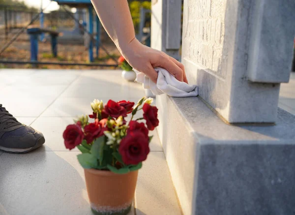Прибирання кладовища. Жіноча рука миє сірий пам'ятник на могилі ганчіркою — стокове фото
