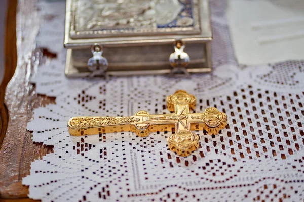 Una gran cruz de oro con un crucifijo sobre la mesa junto a un libro religioso. — Foto de Stock