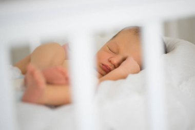 Yeni doğan beyaz karyolada uyur. Sağlıklı çocuk uykusu kavramı.