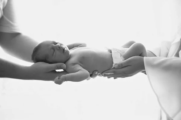 Parents hands hold the newborn against the window background. — Stock Photo, Image