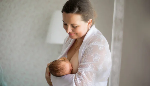 Maman nourrit le nouveau-né debout dans un intérieur blanc. qui allaitent. maternité heureuse — Photo