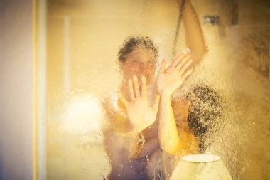 Yumuşak odaklanma. Çıplak adam ve kadın pencereli banyoda birlikte duş alıyor.