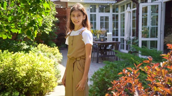 Una adolescente con el pelo largo oscuro en el jardín de una casa. —  Fotos de Stock