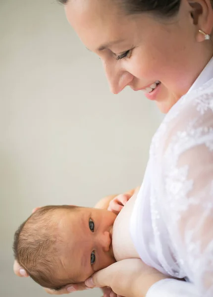 Mamá alimenta al recién nacido de pie en un interior blanco. amamantando. maternidad feliz — Foto de Stock