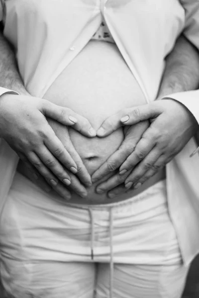 Siyah-beyaz. Erkekler ellerini hamile bir kadının karnına koyar.. — Stok fotoğraf