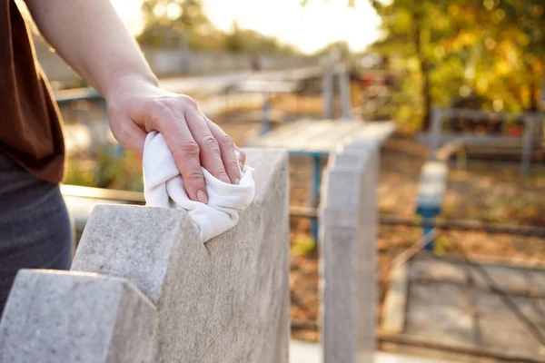 Καθαρισμός νεκροταφείου. Ένα γυναικείο χέρι πλένει γκρι μνημείο στον τάφο με κουρέλι. — Φωτογραφία Αρχείου