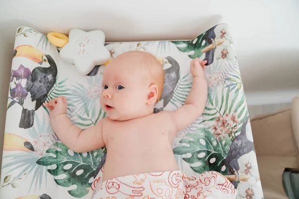 Bebé pelirrojo yace en un cambiador. seguridad para los niños. —  Fotos de Stock