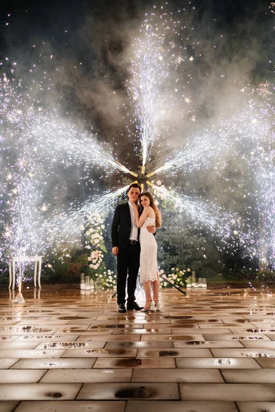 Nevěsta a ženich stojí na chodbě fontán ohňostroje — Stock fotografie