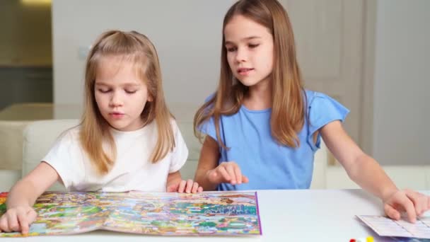 Due ragazze carine considerano un nuovo walker gioco da tavolo. Un regalo per i bambini. — Video Stock