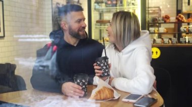 Sevgililer Günü 'nde bir adam ve bir kadın pencerenin yanındaki kafede gülüyorlar.