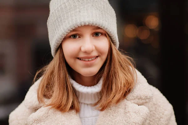 Ein hübsches Teenager-Mädchen hält ihre Hände auf einer warmen, grauen Strickmütze. Neues Jahr. — Stockfoto