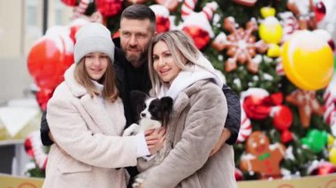Sokakta Noel ağacının yanında köpeği Papillon olan güzel bir aile. fotoğraf çekimi