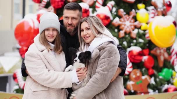 Bella famiglia con cane Papillon vicino all'albero di Natale sulla strada. servizio fotografico — Video Stock